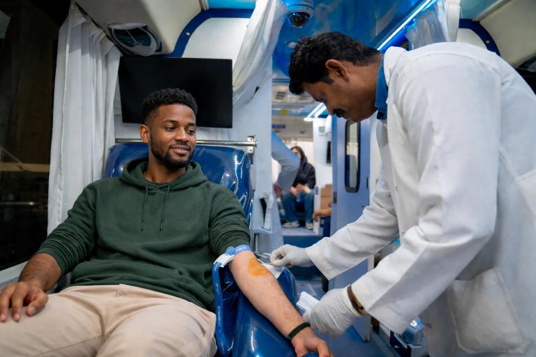 Man donating blood in a mobile clinic.