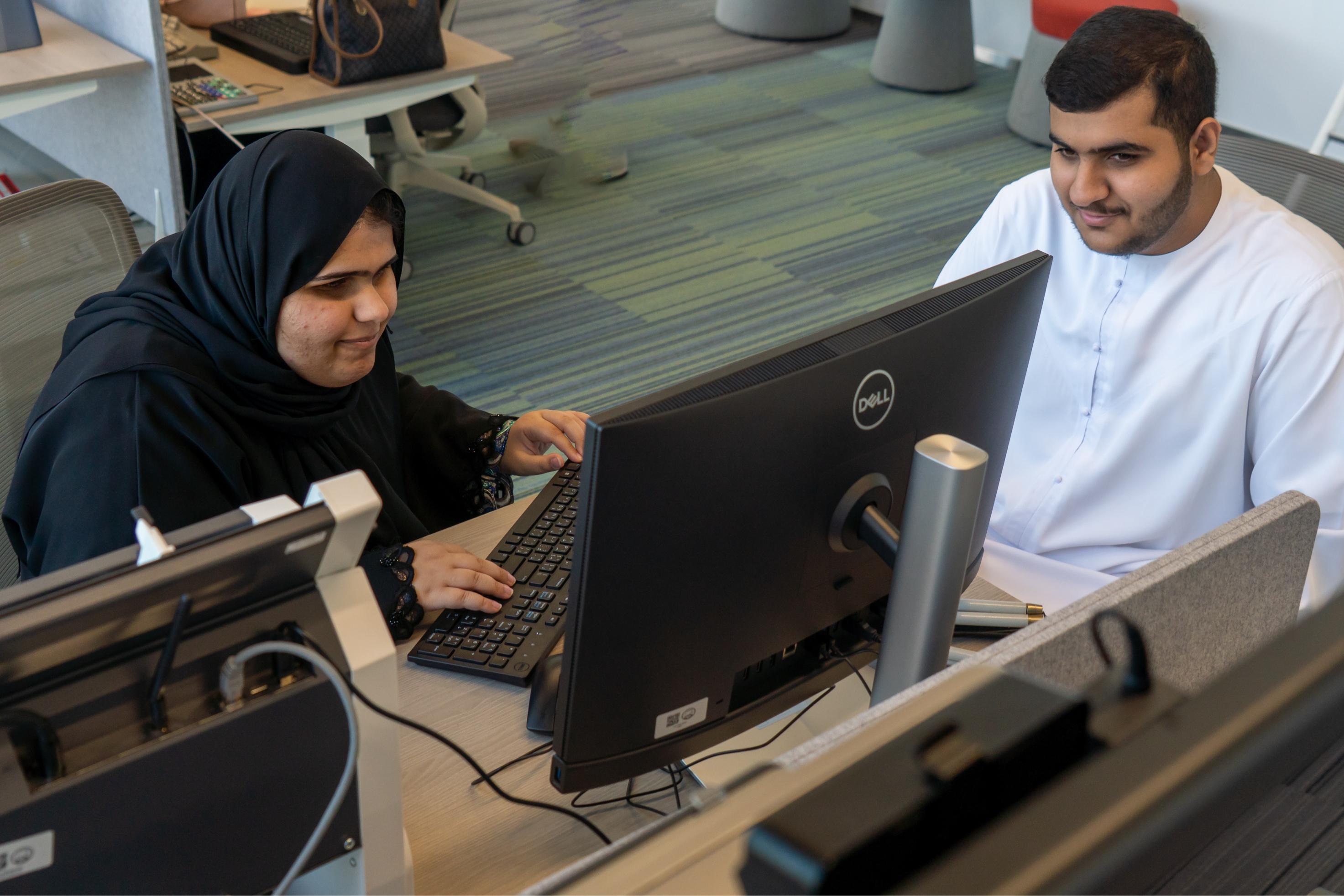 Two people working at computers in an office.