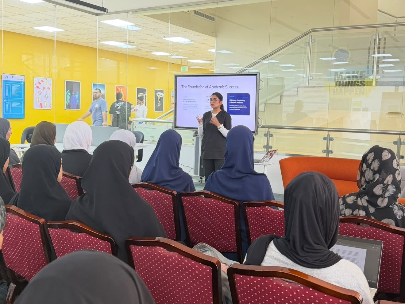 Woman giving presentation to seated audience.